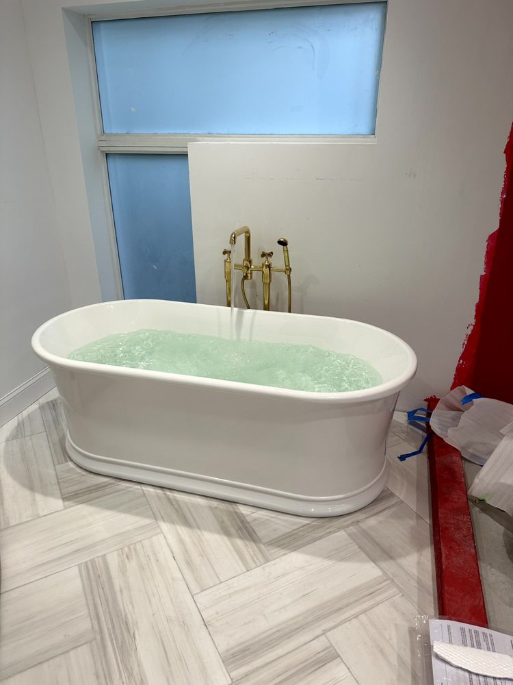 White freestanding bathtub filled with water.