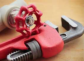 Red pipe wrench and valve wooden surface